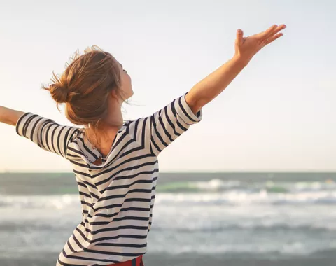 young woman at the beach arms open