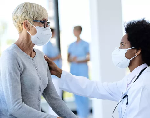 Doctor speaking with patient; both in masks